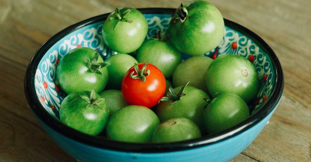 green tomatoes in a cyan bowl